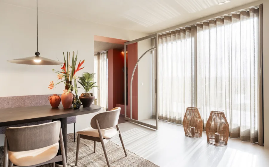 Eethoek met gebogen houten meubels en glazen deur in steel look met vloeiende lijnen.