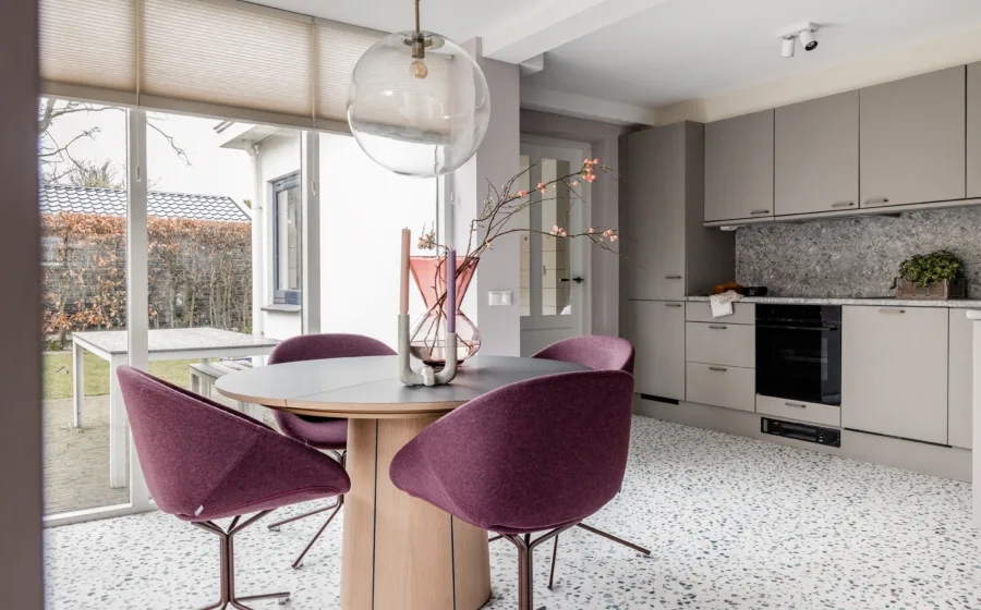 Keuken met natuursteen look vloer en ronde tafel met 4 stoelen op bronzen poten.