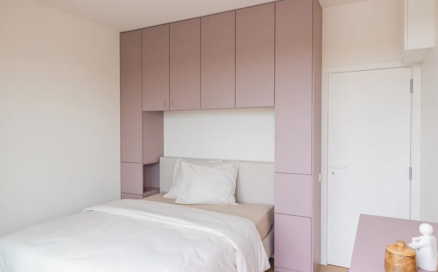 Slaapkamer met kamerhoge roze kast op maat voor extra opbergruimte. | Aanhuis.be