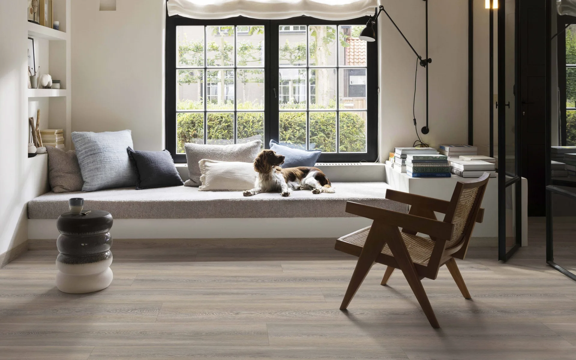 Woonkamer met houtlook vinyl vloer, knusse bank en sfeervolle vouwgordijnen.