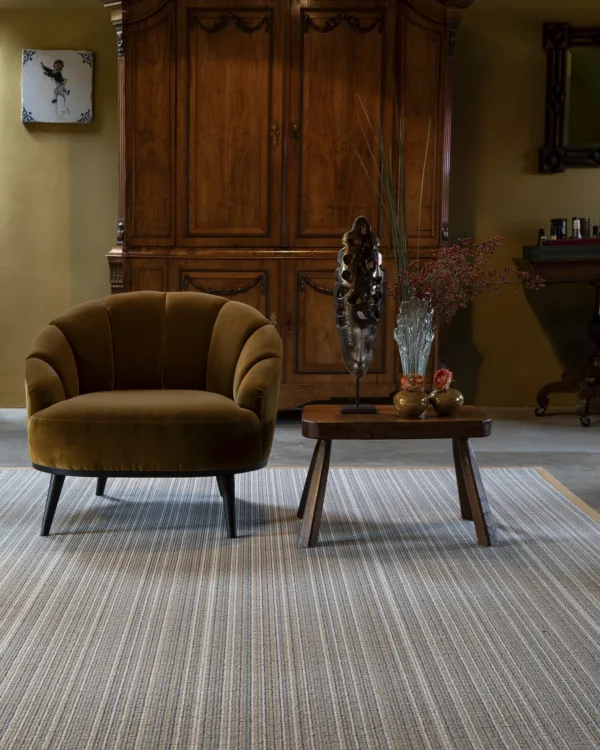 Woonkamer met klassiek interieur, houten linnenkast, fluwelen fauteuil, salontafel en rechthoekig vloerkleed van wol.