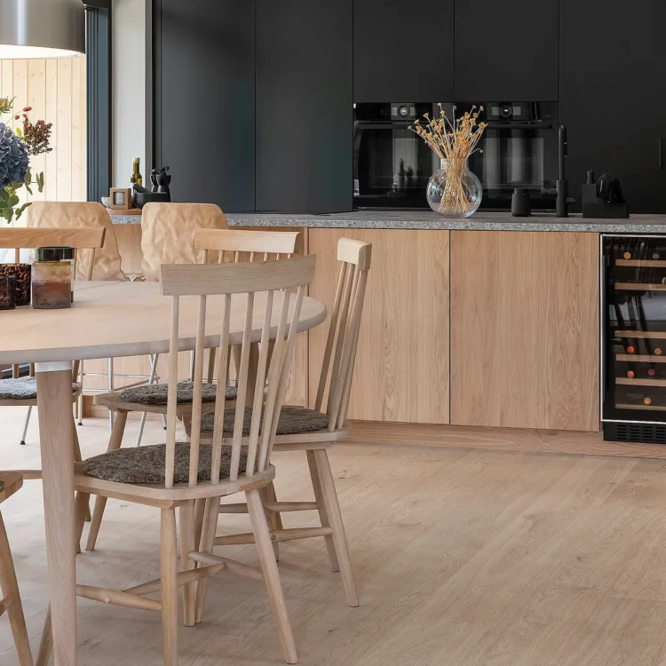 Keuken met lichte kleur fineerparket en lichte kleur houten tafel en stoelen, wijnkoeler en marmeren blad op keukenblok