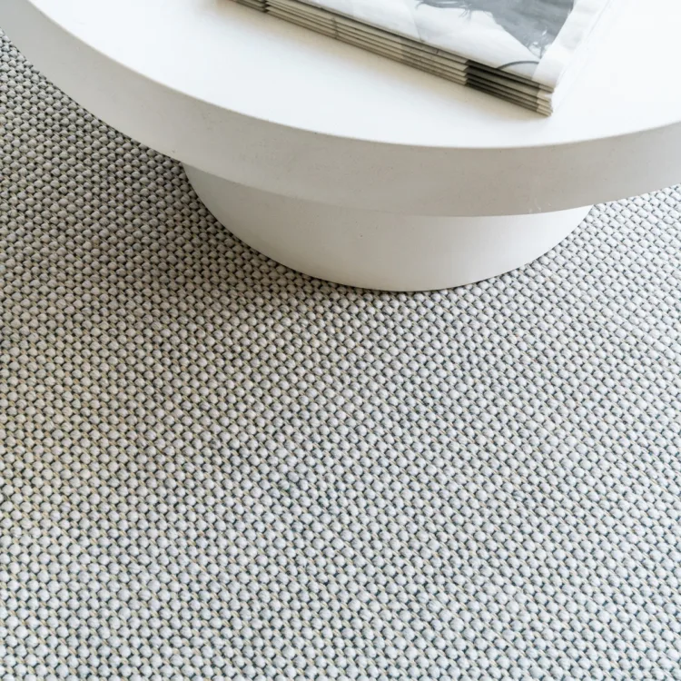 Lichte grijze wol tapijt met bolletjes en een wit tafeltje