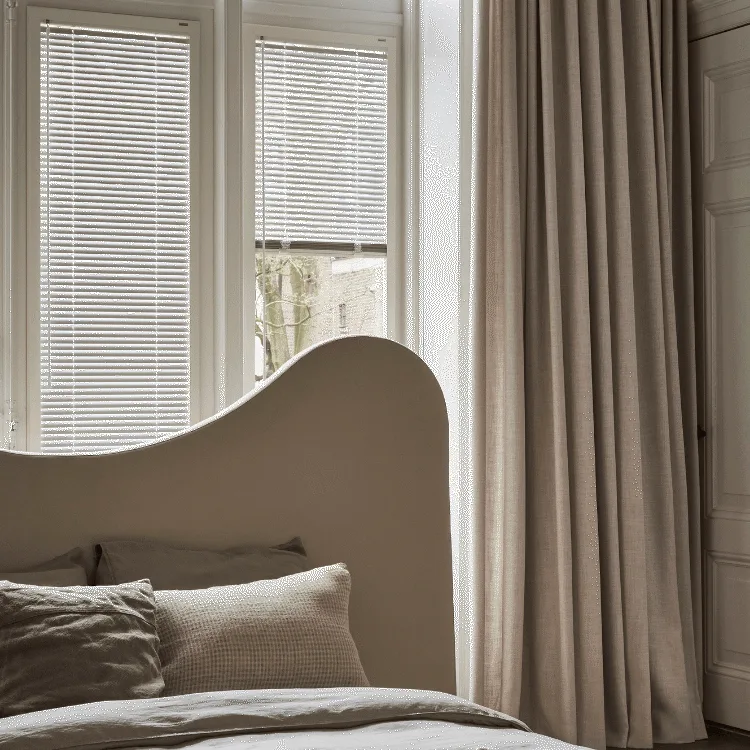 Witte jaloezieën met beige overgordijnen in de slaapkamer