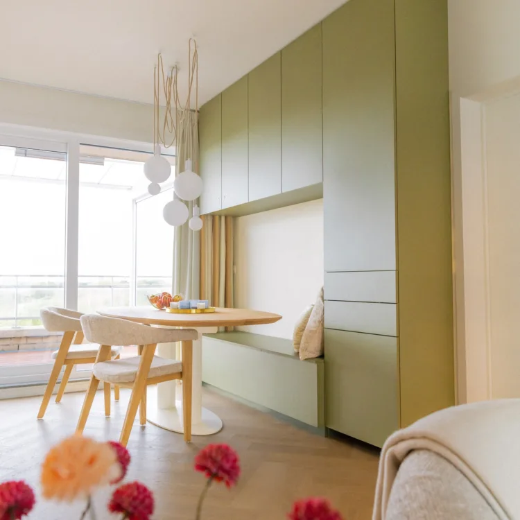Woonkamer met praktische kast op maat, zitplek, ovale tafel en houten vloer, scandinavische stijl. | Aanhuis.be
